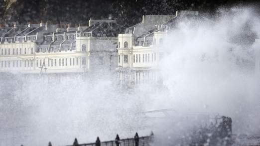 Waves crash over the sea wall in Dover