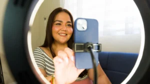 Getty Images A young woman sets up her phone on a tripod with a ring light around it.