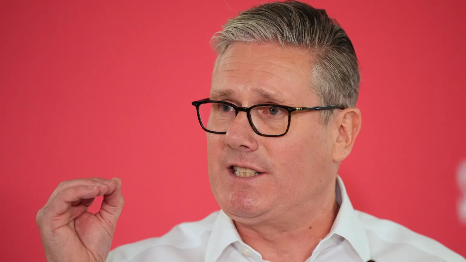 PA Media Sir Keir Starmer speaking on Monday. He is wearing a white shirt, open at the neck, and gesturing with his hand.