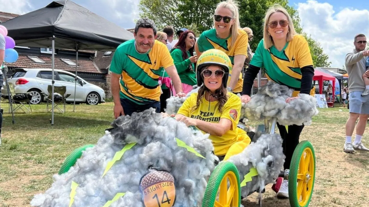 People dressed in yellow and green and their soapbox derby entry