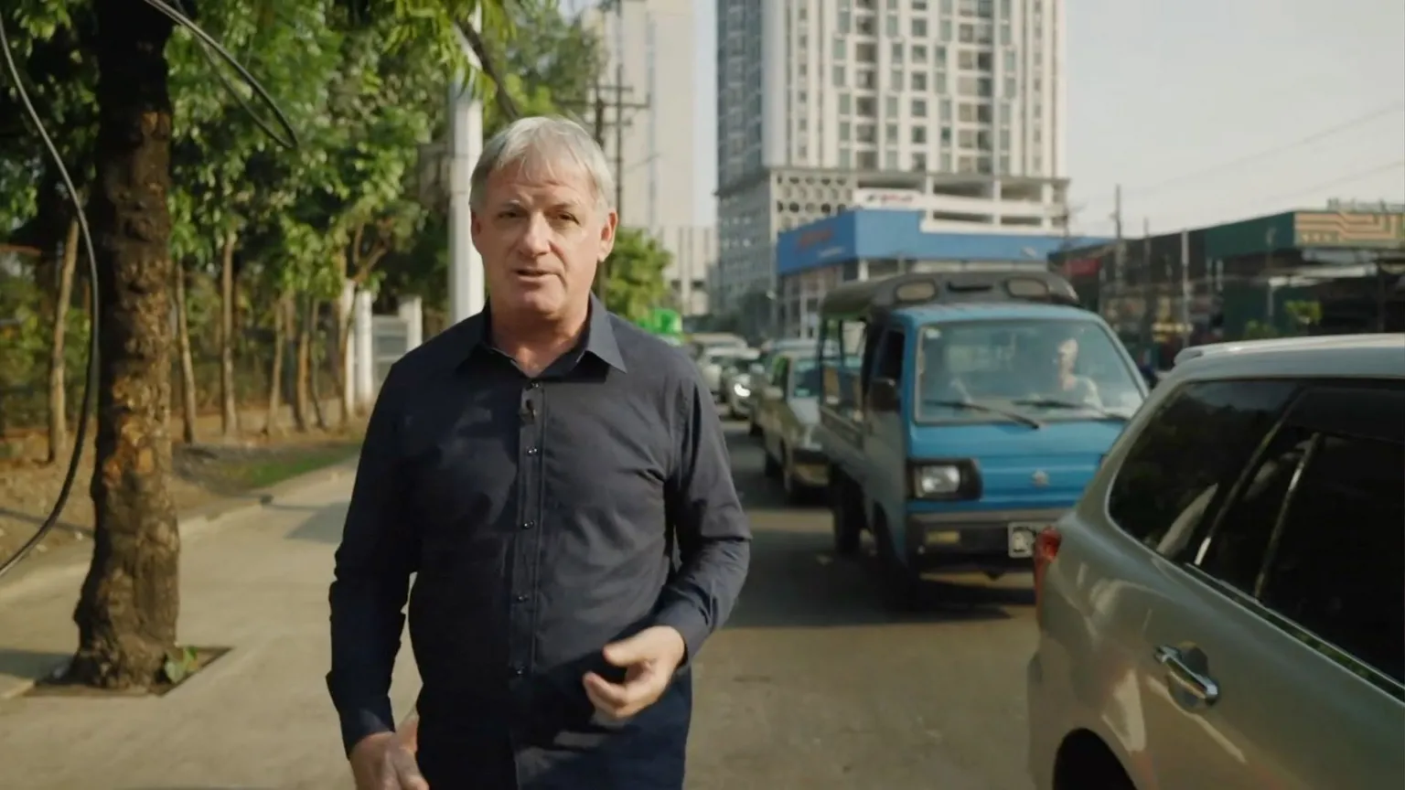 Jonathan Head walking next to queue of cars waiting for fuel