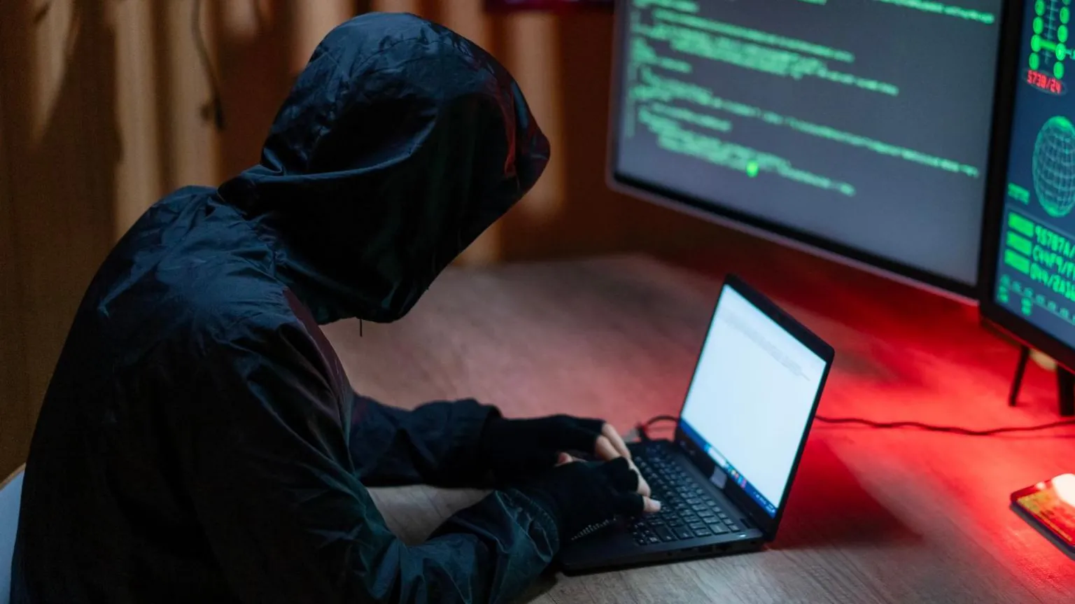 A man in dark clothing posing as a cyber-criminal