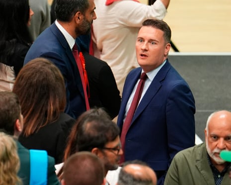 A high-angle shot of Wes Streeting looking agape across a crowd of people at an election count