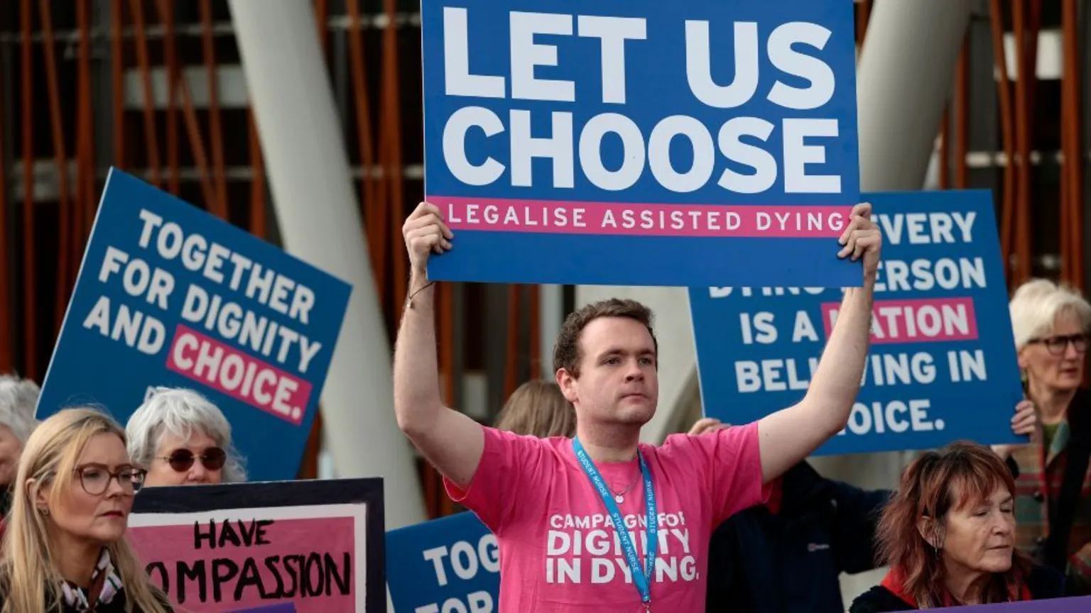 Getty Images Protesters hold colourful signs in favour of assisted dying