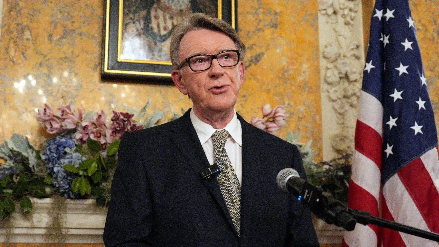 Reuters Lord Mandelson speaks into a microphone at the ambassador's residence in Washington. Behind him is a US flag, flowers and a painting on yellow wallpaper.