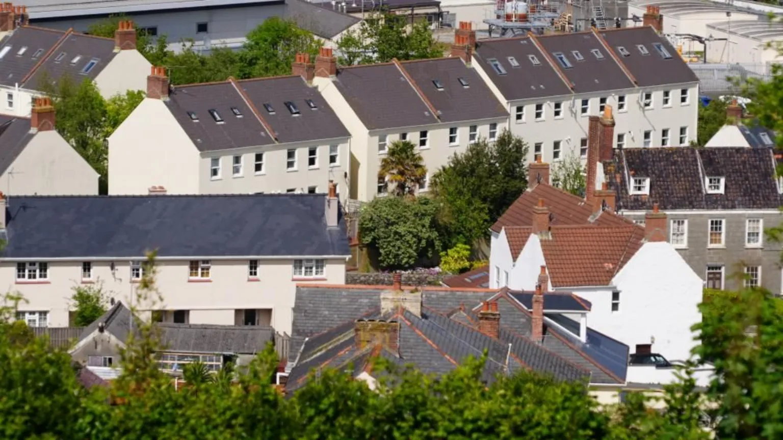 An image of houses in Guernsey taken from above, with grey roofs and white walls and trees peppered between them.