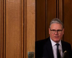 Keir Starmer beside a wooden panelled door.
