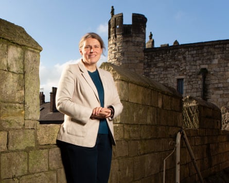 Rachael Maskell stands in front of a stone rampart at a castle in York. She wears a pale cream jacket and has long fair hair, tied back. The sky is blue behind her.