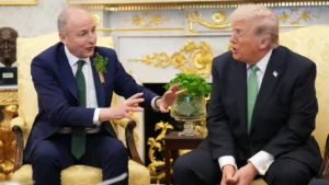 Niall Carson/PA Wire Martin and Trump are sitting next to each other in a room with a fire place, a bust of a head and a glass vase. Martin's hands are up as he talks.