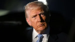 Getty Images Trump wearing a black suit and blue tie looks into the distance. The background is black.