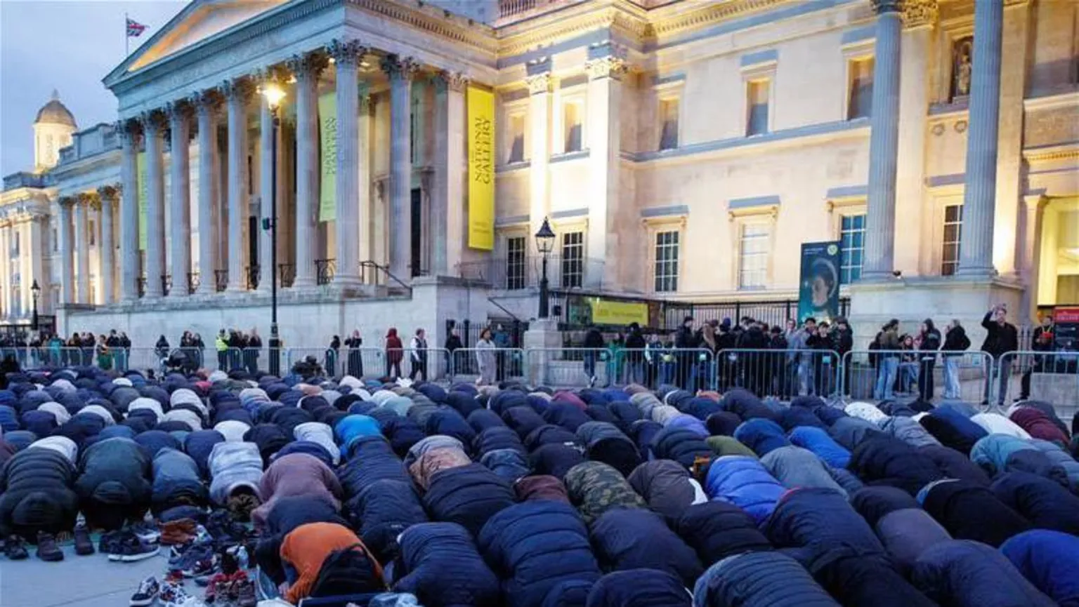 PA Media Dozens of people bowed in prayer, as the sun sets over the National Gallery building in Trafalgar Square