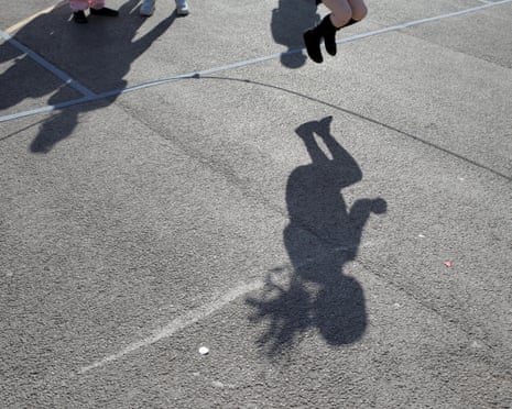 The shadow of a child skipping in a playground.
