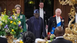 PA Media The Princess of Wales in a green dress President of Nigeria Bola Ahmed Tinubu in navy blue and King Charles III in a black suit stand at the table which is decorated with gold features and spring flowers