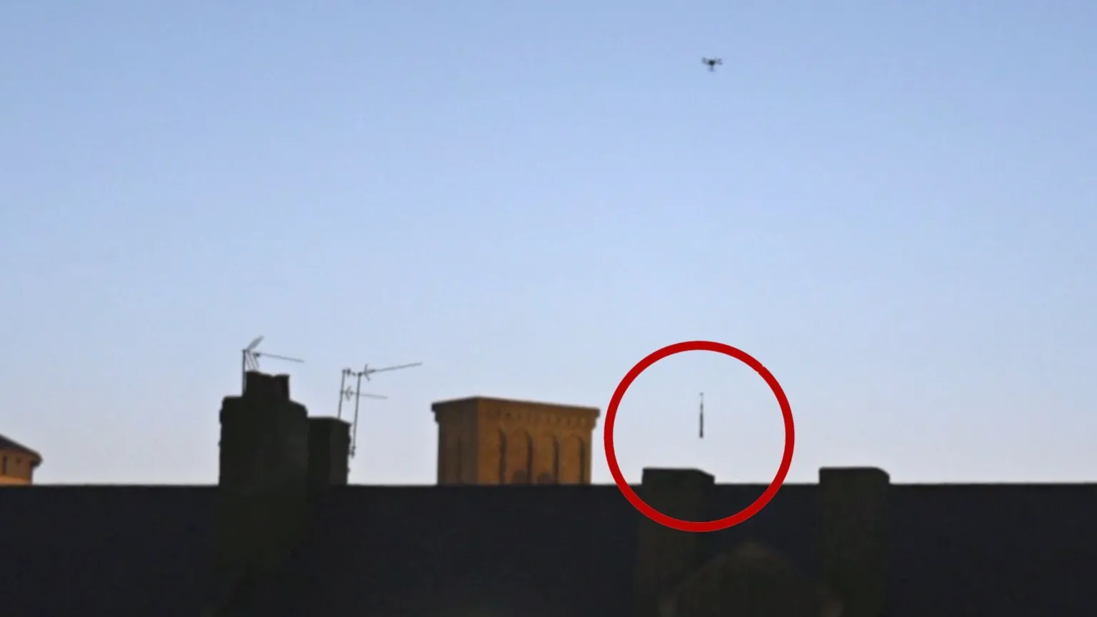 Drone dropping package behind wall - the package is circled in red