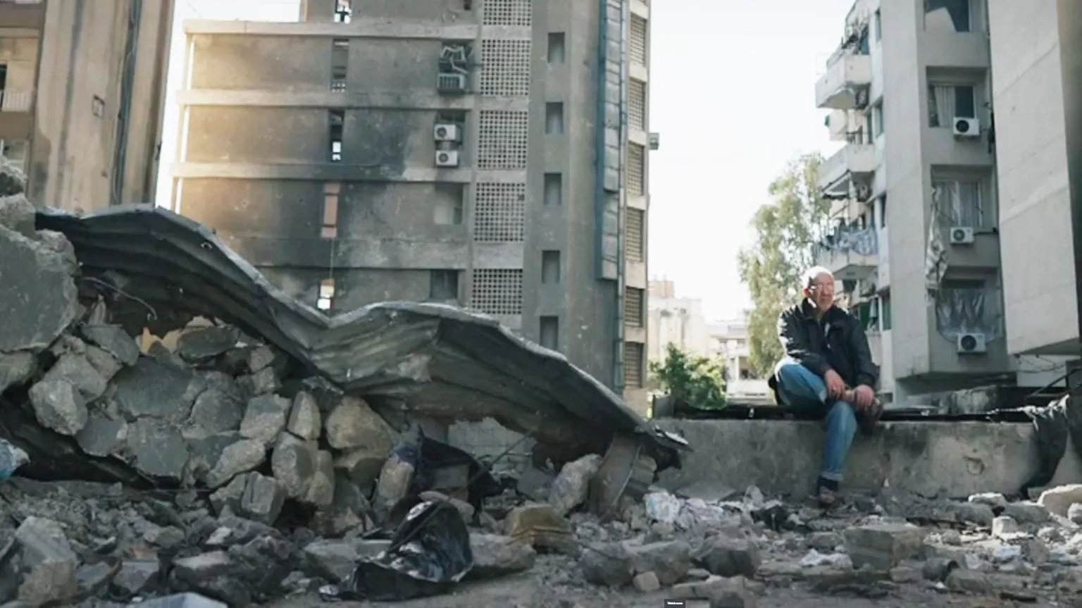 A man sits in rubble in corniche al mazraa