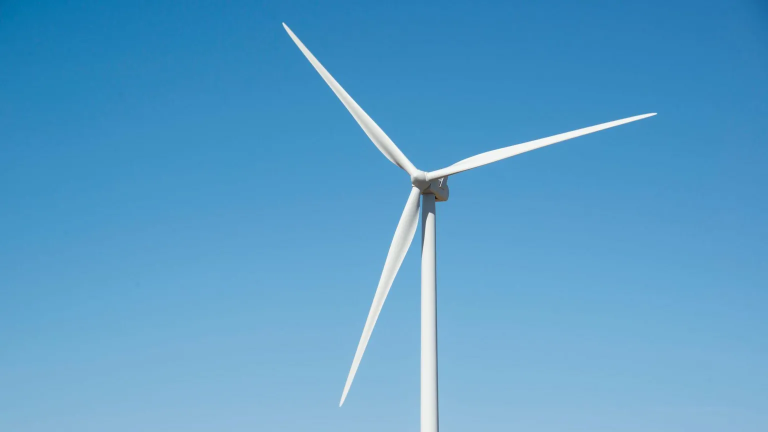 A lone wind turbine against a blue sky