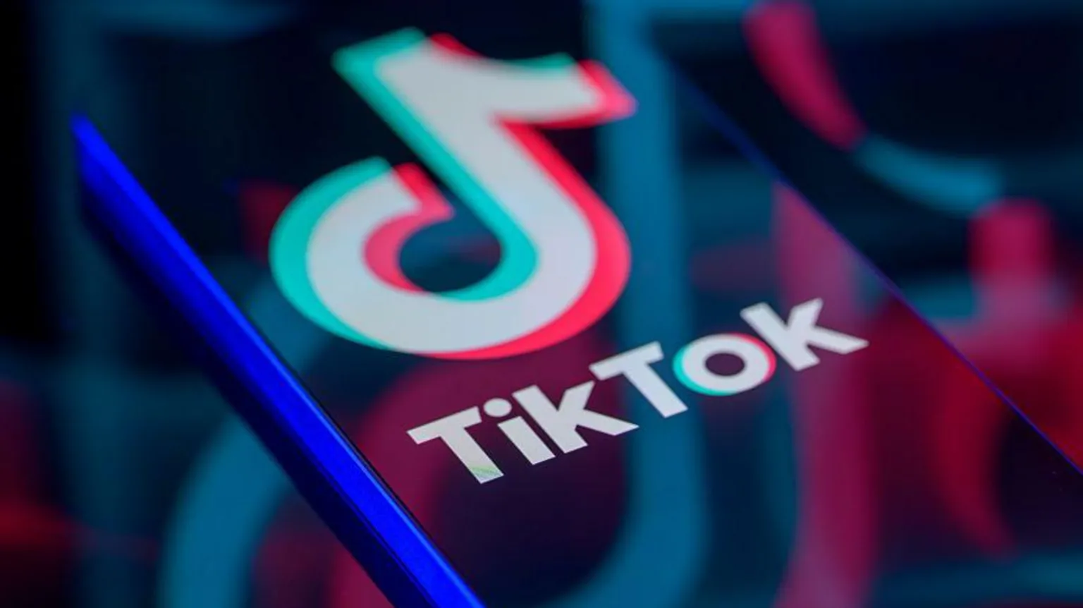 Getty Images TikTok logo displayed on a smartphone screen, with enlarged, faded versions of the logo reflected across it.