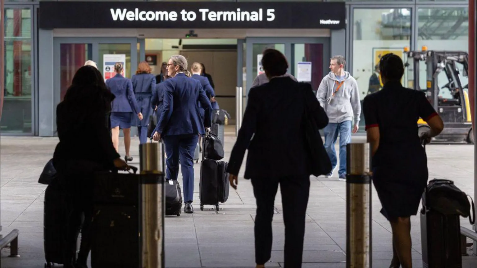 Getty Images Passengers and airline staff outside Terminal 5 carrying suitcases and other luggage.