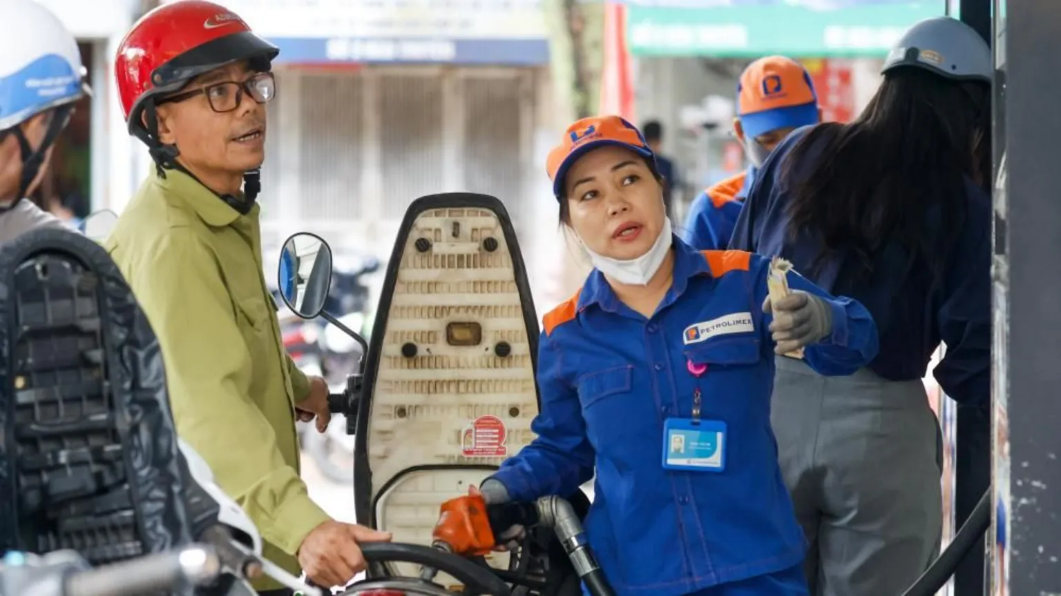 An employee pumps fuel into a customer's motorbike at a petrol station in Hanoi, Vietnam