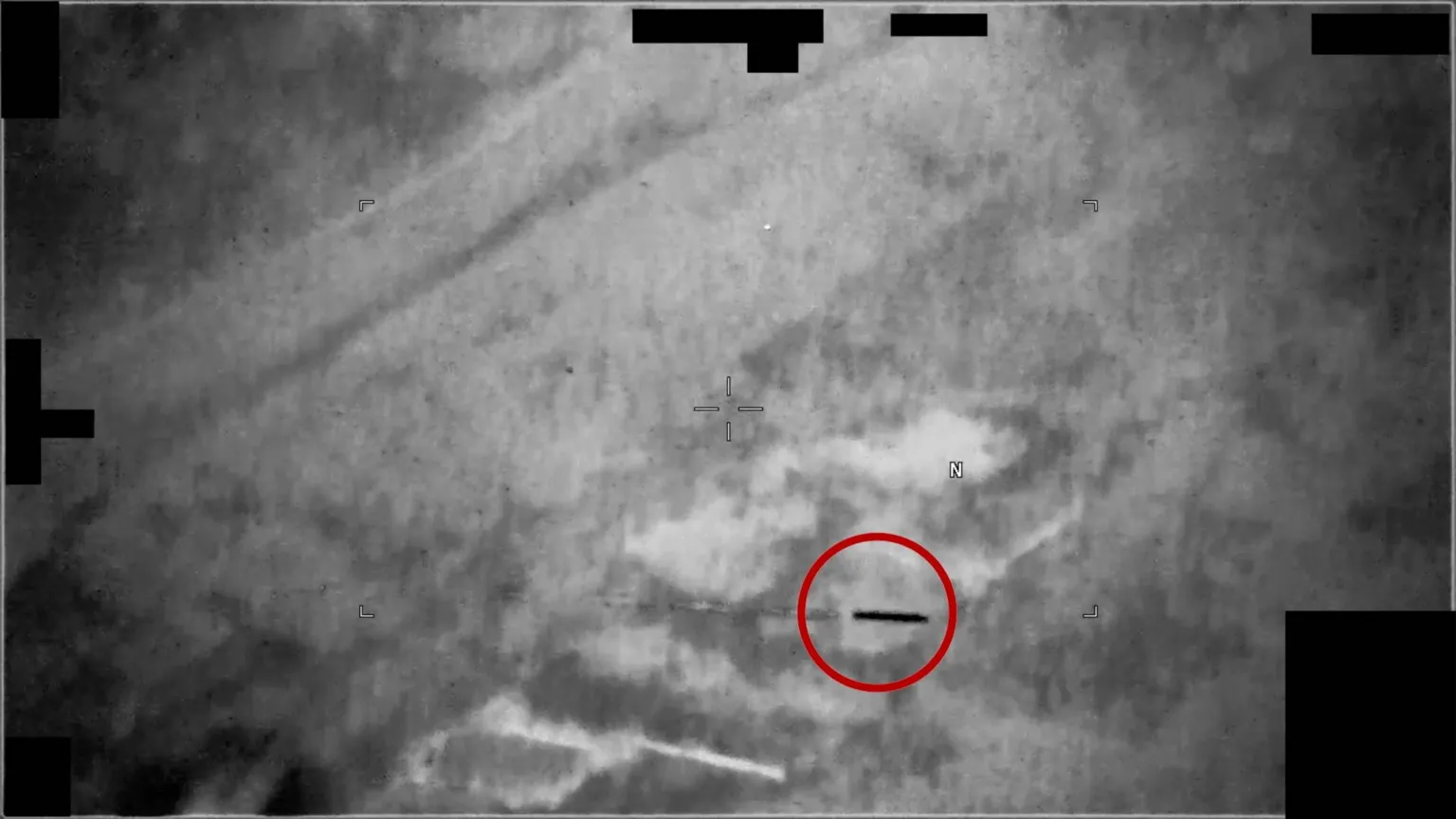 An unidentified black, tubular thing shoots through the air. There is a red ring around it.