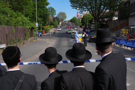 Members of the community watch as forensic officers search the area after two people were stabbed in the Golders Green neighbourhood, that has a large Jewish community, in London.