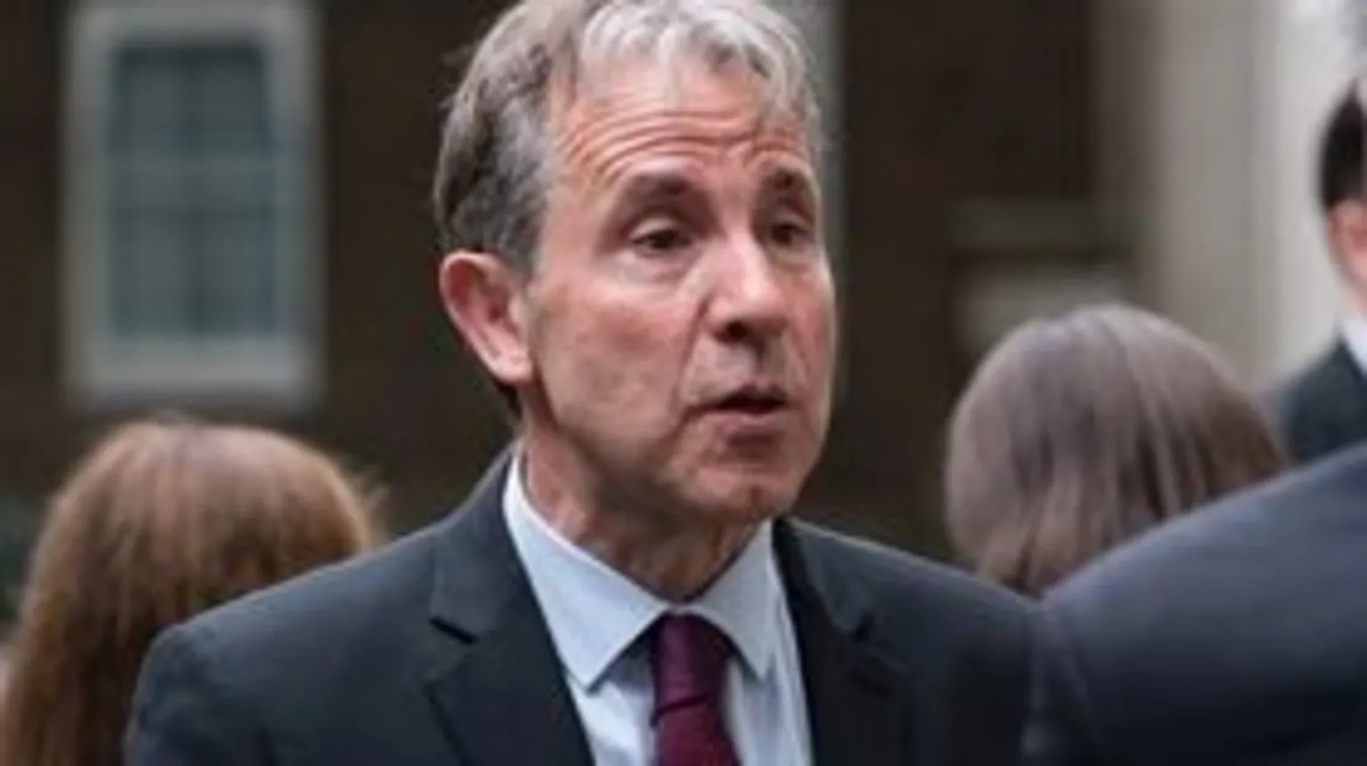 Dan Norris wearing navy suit and red tie and light blue skirt