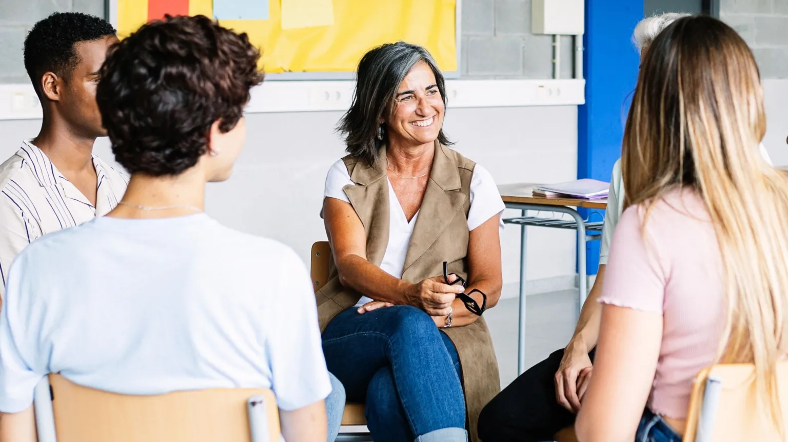 Getty Images A smiling lady leads a discussion with four other people sitting in a circle