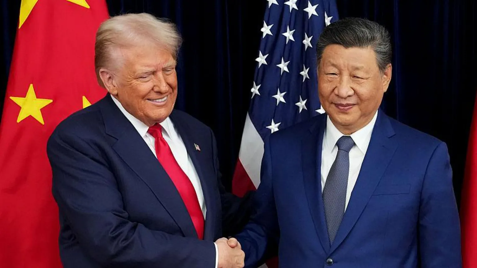US President Donald Trump exchanges a handshake with Chinese President Xi Jinping while posing for pictures in front of their countries' national flags