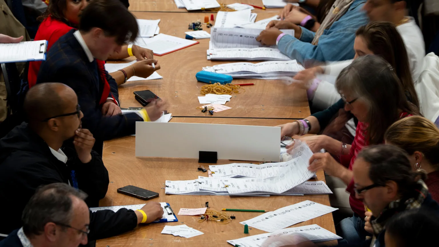 PA Media People sitting across a long table count ballot papers in Westminster, central London.