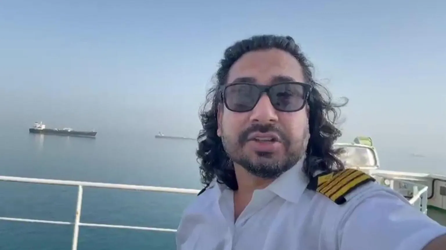 Captain Raman Kapoor on board his ship with the Strait of Hormuz in the background