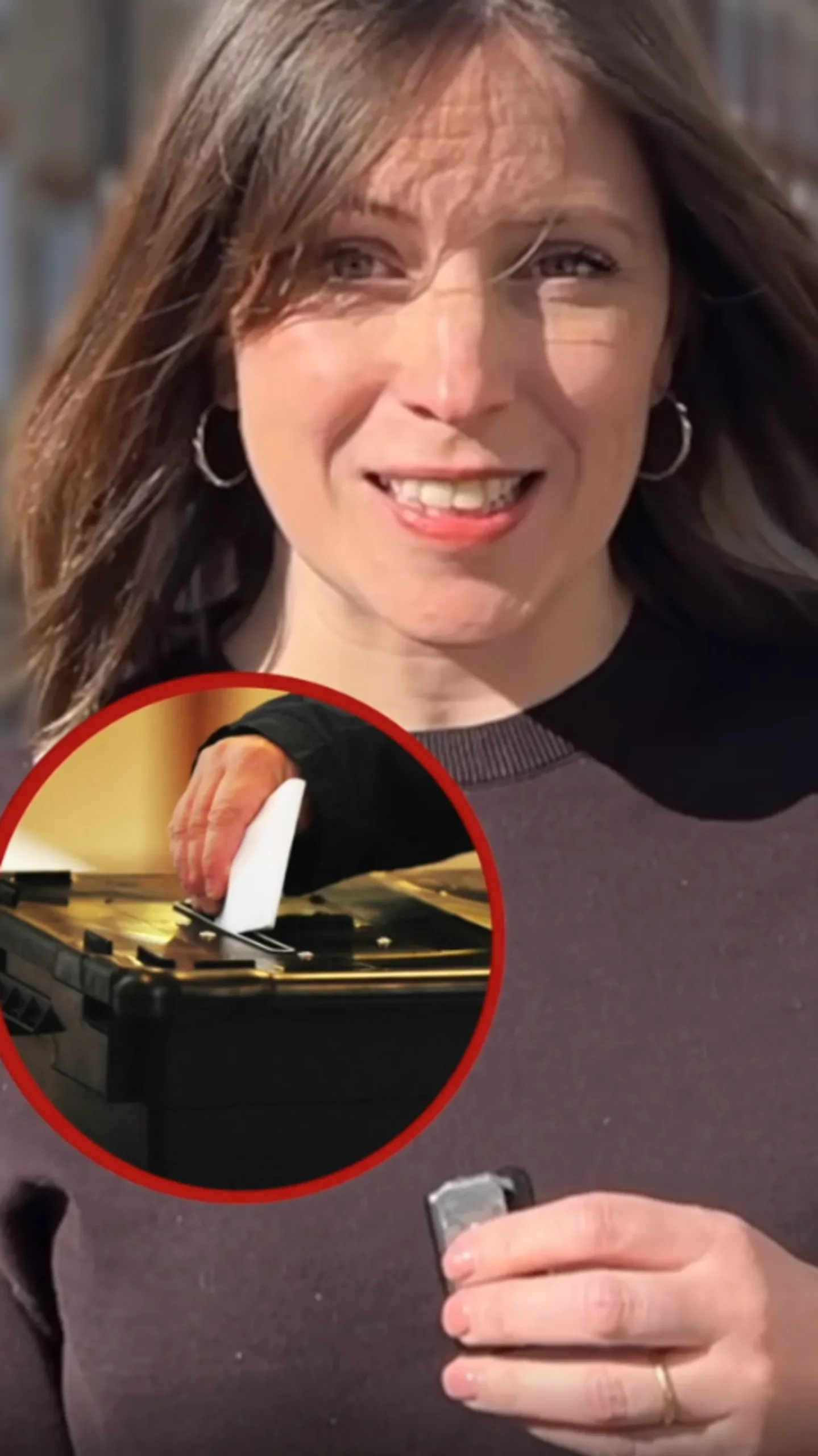 A reporter looks at the camera while talking. She is wearing a brown t-shirt and has short brown hair. There is a circular image of a person placing a ballot paper into a ballot box inset in the picture.