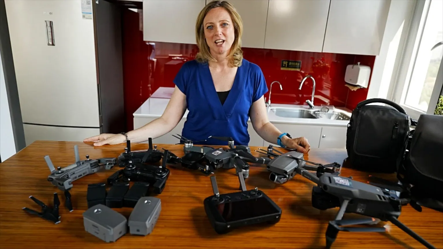 Laura Bicker, wearing a dark blue top, standing in front of a table with several drone devices on it.