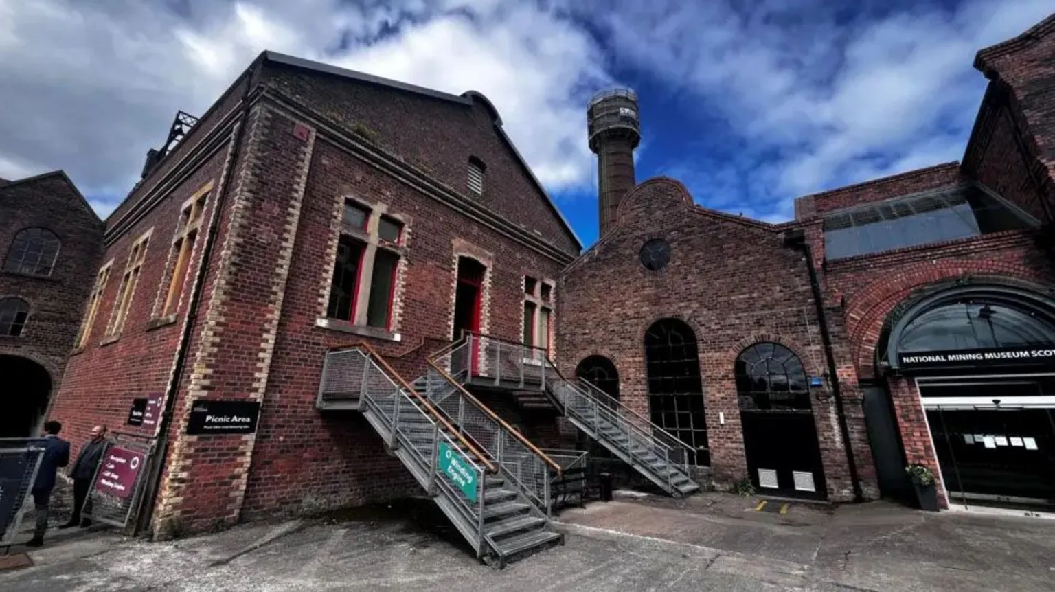 The brick boiler house in front of a large tower against a blue sky