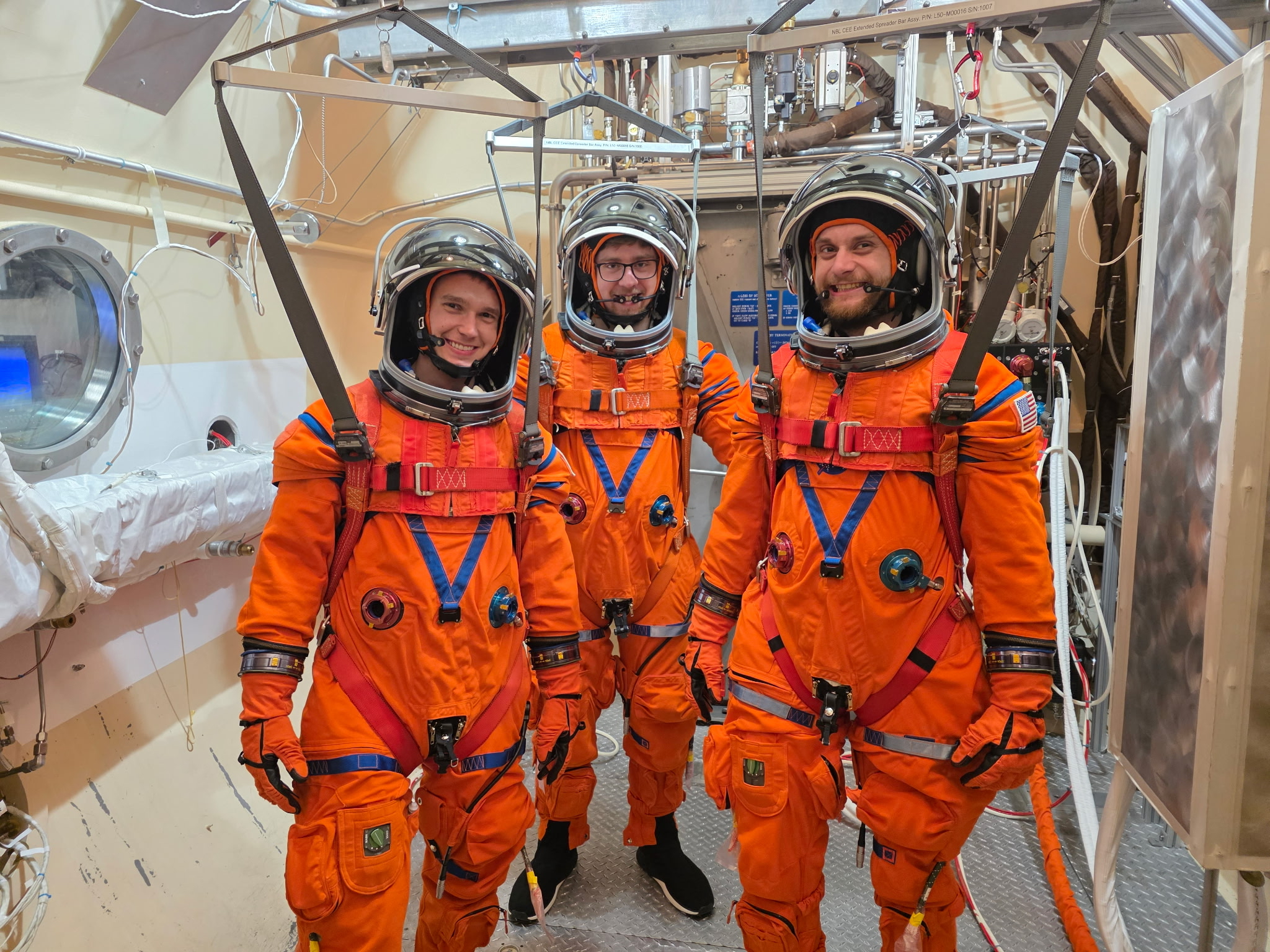 Four people pose in a laboratory setting. They are all wearing