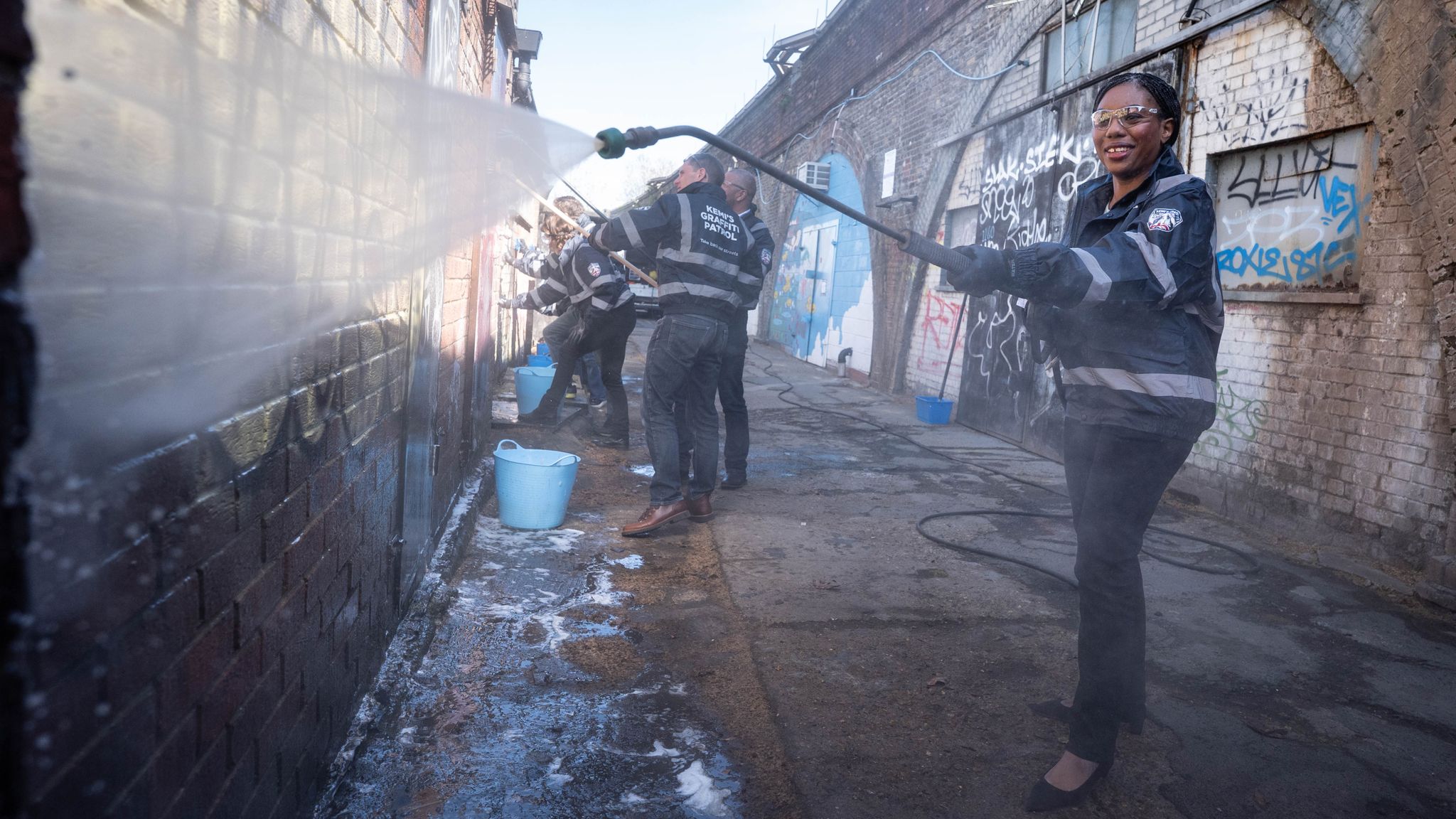 Kemi Badenoch cleans graffiti off a wall in Herne Hill, south London, on Tuesday. Pic: PA