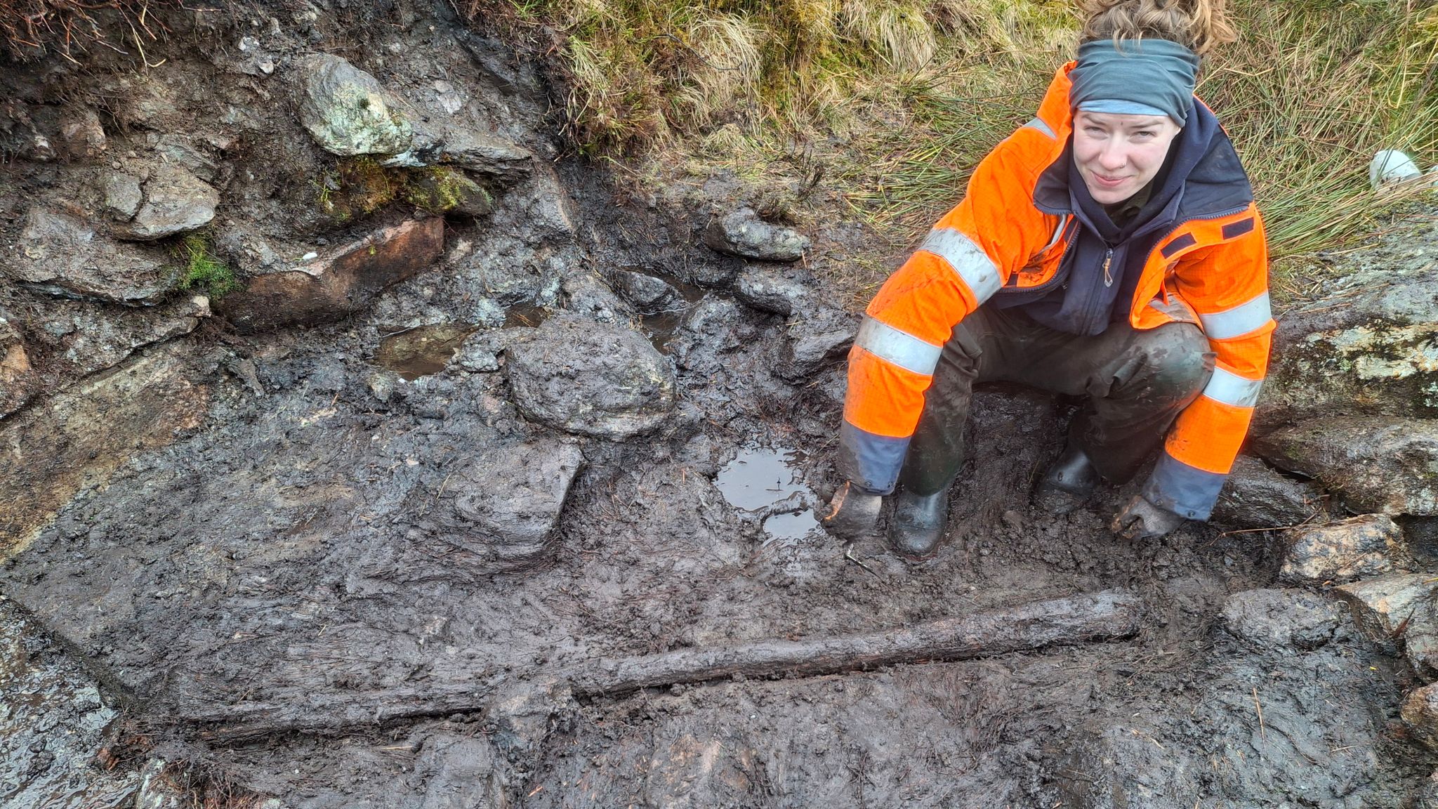 Archaeology trainee Alice Connelly with a timber post found at the illicit whisky still site. Pic: NTS/PA